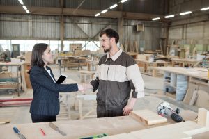 Pretty young female manager or business partner shaking hand of worker